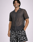 Man wear a sheer grey short sleeve button up shirt and RF-Wear Men's Mesh Flame Shorts in Black/Grey