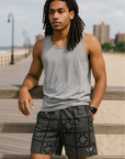 Man Standing on walkway near city beach wearing a grey tank top and RF-Wear Men's Bandana Patchwork Shorts in Black.