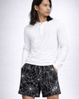 Man wearing a white top and RF-Wear men's spider Web shorts in Black