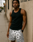 Man standing on city street wearing a black tank top and RF-Wear Men's Mesh Bandana Shorts in White.