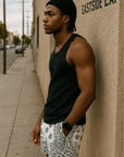 Man standing on city street wearing a black tank top and RF-Wear Men's Mesh Bandana Shorts in White.