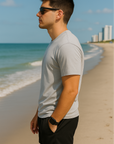 Man standing on beach wearing a grey t-shirt and RF-Wear men's mesh solid color shorts in black - side view.