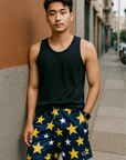 Man wearing a black tank top and navy shorts with star patterns on a city street.
