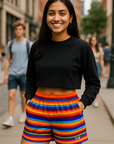 Person wearing a black crop top and colorful striped shorts on a city street.