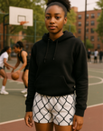 Person wearing a black hoodie and white shorts with black chain link pattern on a basketball court.