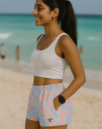 Woman in athletic wear standing on a beach with turquoise water and clear sky.