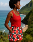 Woman in a red top and floral shorts standing in a scenic location with ocean and mountains.