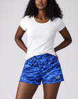 Woman wearing a white t-shirt and RF-Wear Women's Mesh Tiger Camo Shorts in Blue