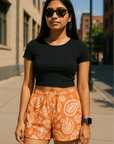 Woman standing in city wearing RF-Wear Women's Paisley Shorts - Apricot/Cream - Front View