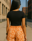 Woman standing in city wearing RF-Wear Women's Paisley Shorts - Apricot/Cream - Back View