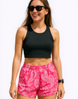 Woman wearing a black top and RF-Wear Women's Paisley Shorts in Fuchsia/White