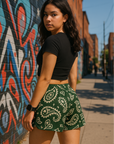 Woman standing on sidewalk wearing RF-Wear Women's Paisley Shorts - Pine/Cream - Back View