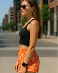 Woman standing on street in city wearing RF-Wear Women's Paisley Shorts - Orange /White - Side View