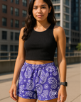 Woman standing on the city street wearing RF-Wear Women's Paisley Shorts - Purple/White - Front View