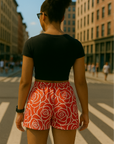 Woman in black top and RF-Wear women's red/white rose shorts standing on a city street.