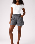 Woman wearing a white top and RF-Wear women's black snakeskin shorts