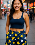 Woman wearing a navy blue crop top and star-patterned shorts in a city street setting.