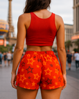 Person wearing a red tank top and orange shorts with star pattern in an urban setting