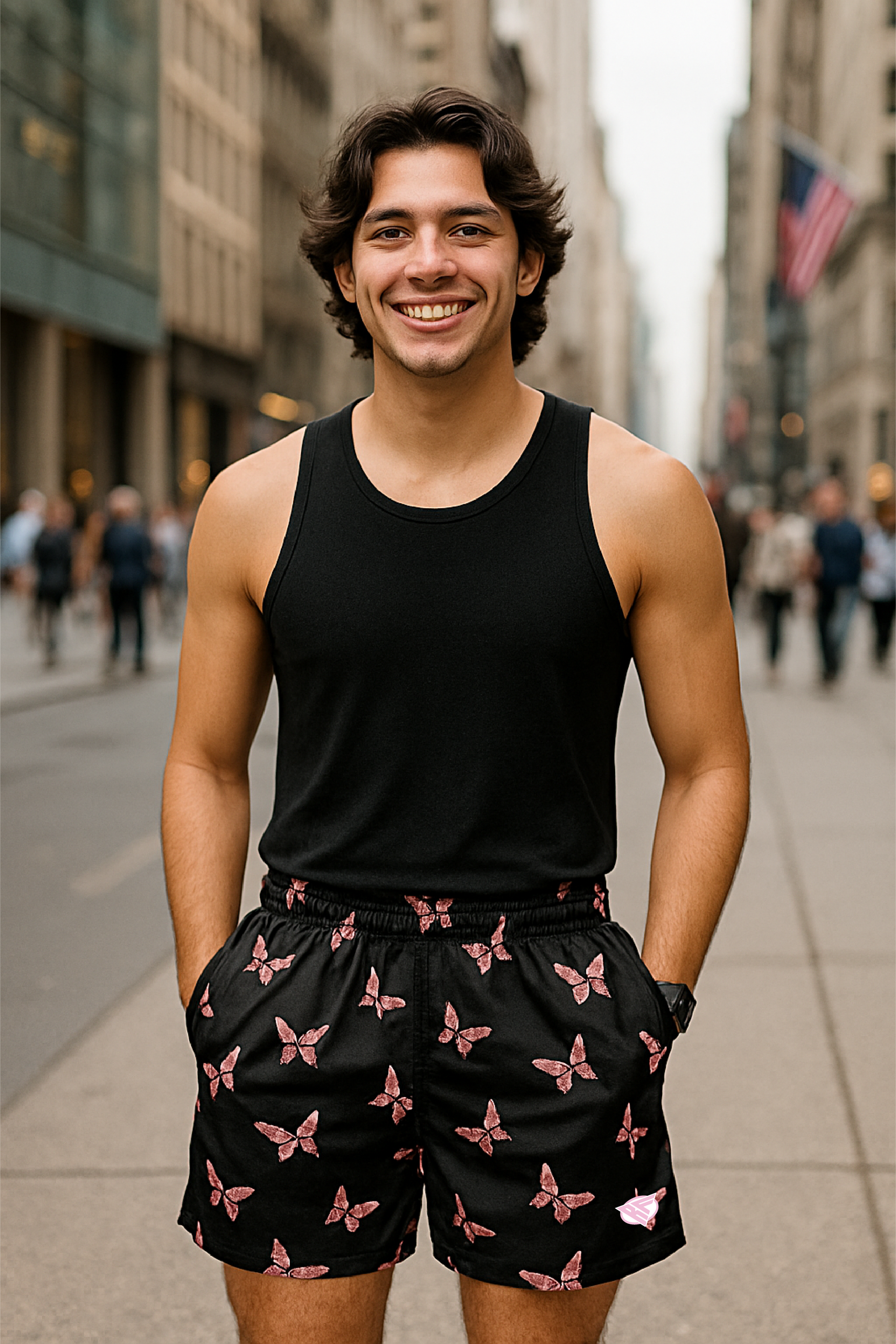 Man wearing a black tank top and butterfly patterned shorts on a city street