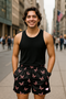 Man wearing a black tank top and butterfly patterned shorts on a city street