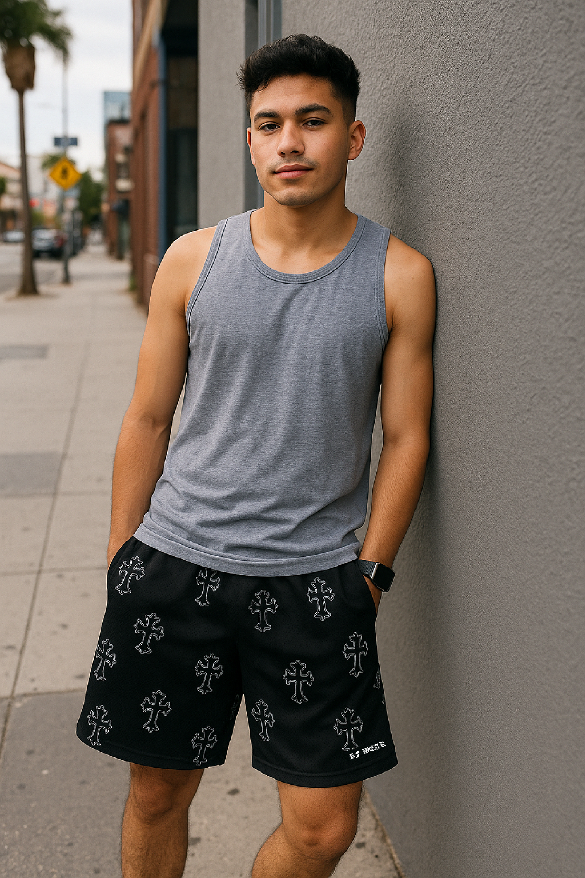 Man leaning against city wall with grey tank top and RF-Wear Men's Mesh Cross 3.0 shorts.