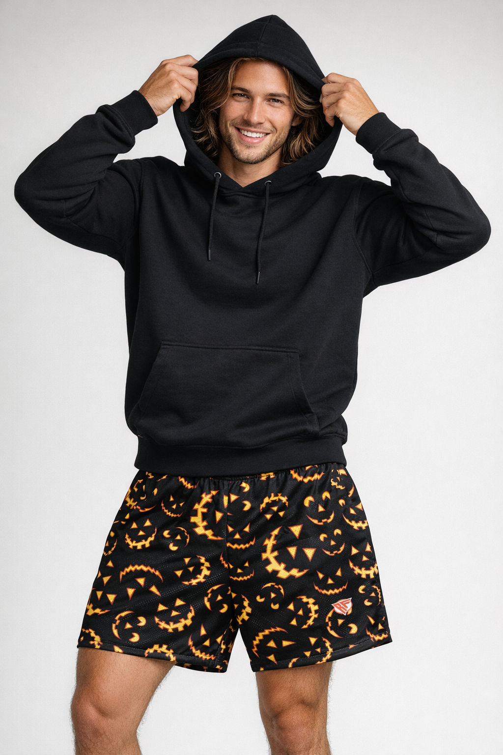 Man wearing a black hoodie and RF-Wear Men's Mesh Jack-O-Lantern 2.0 Shorts in Black/Orange