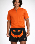 man wearing an orange short sleeve quarter zip top and RF-Wear Men's Mesh Jack-O-Lantern Face Shorts in Black/Orange 