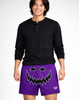 Man wearing a long sleeve black top and RF-Wear Men's Mesh Jack-O-Lantern Shorts in Purple/Black