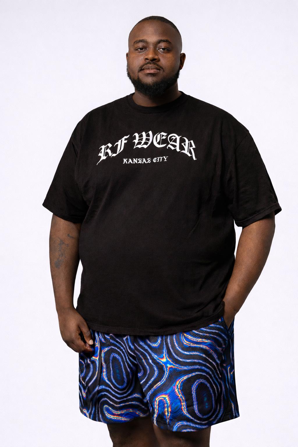 Man wearing a black top and RF-Wear Men's Mesh Psychedelic Shorts in Black/Multicolor