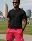 Man wearing a black t-shirt and RF-Wear Men's Mesh Solid Color Shorts in Fuchsia 