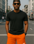 Man wearing a black t-shirt and RF-Wear Men's Mesh Solid Color Shorts in Orange