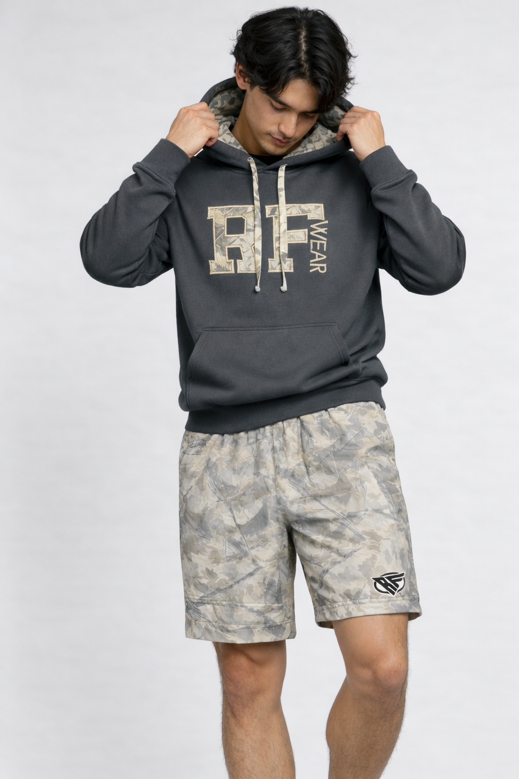 Man wearing a grey hoodie and RF-Wear Men's Mesh Tree Camo Shorts in Cream/Grey