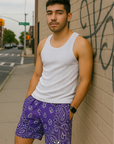 Man leaning against wall on city sidewalk wearing RF-Wear Men's Mesh Bandana Shorts in Purple. 