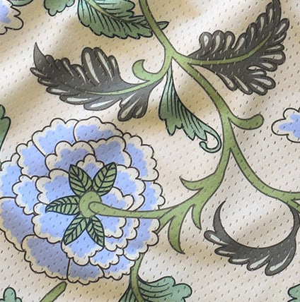 Close-up of floral pattern with blue flowers and green leaves on a beige background