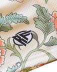 Decorative fabric with floral patterns and a brand logo on a beige background