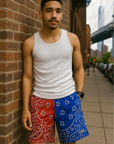 Man leaning against street wall wearing RF-Wear Men's Mesh Split Bandana Shorts - Red/Blue. 