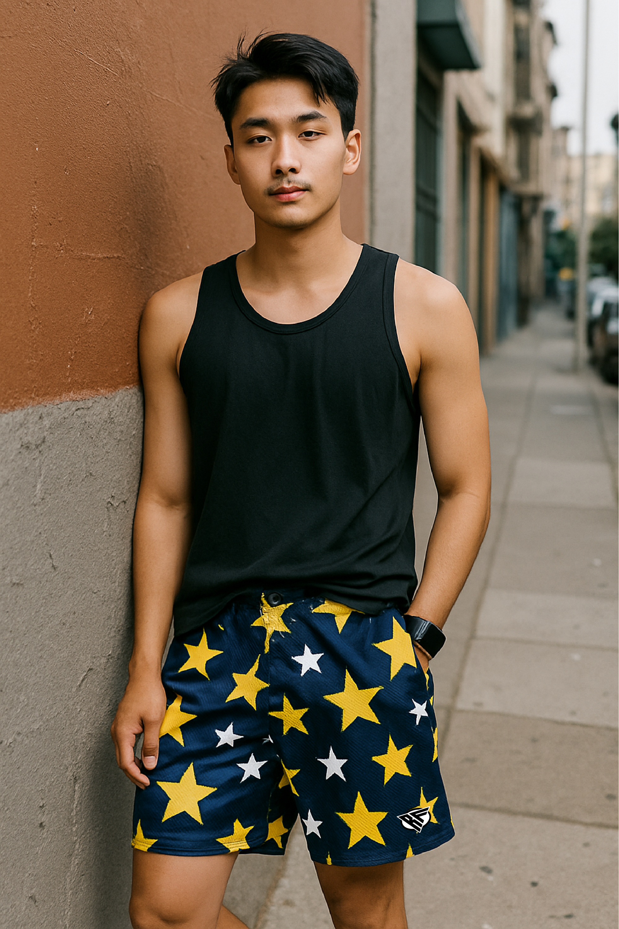 Man wearing a black tank top and navy shorts with star patterns on a city street.