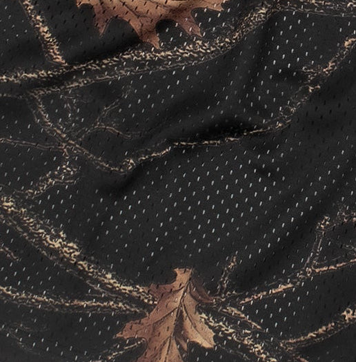 Close-up of black fabric with beige leaf patterns and a single brown leaf on top.
