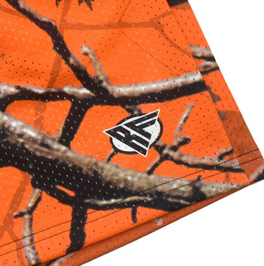 Orange camouflage shorts with tree branch pattern on a white background