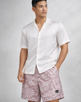 Man wearing a white silk top and RF-Wear Paisley Shorts in Mauve/White