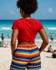 Person wearing a red shirt and colorful striped shorts on a beach