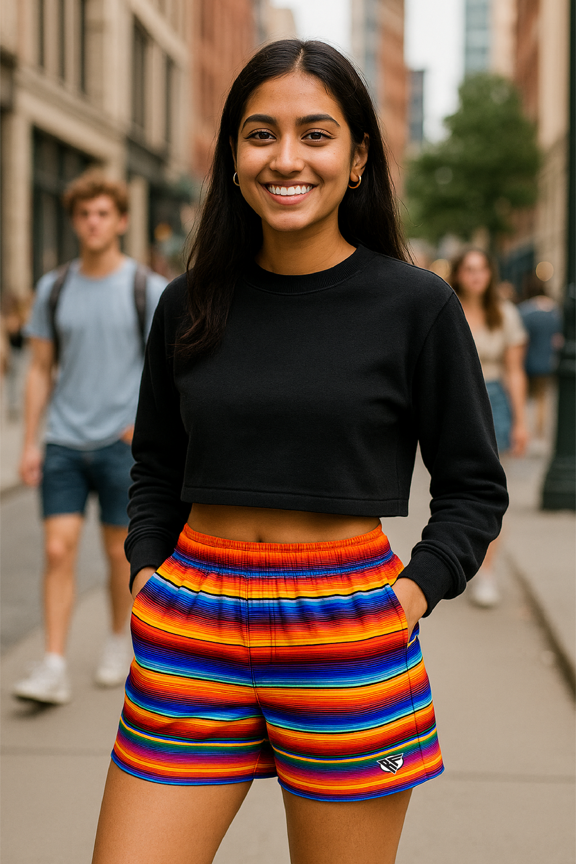 Person wearing a black crop top and colorful striped shorts on a city street.