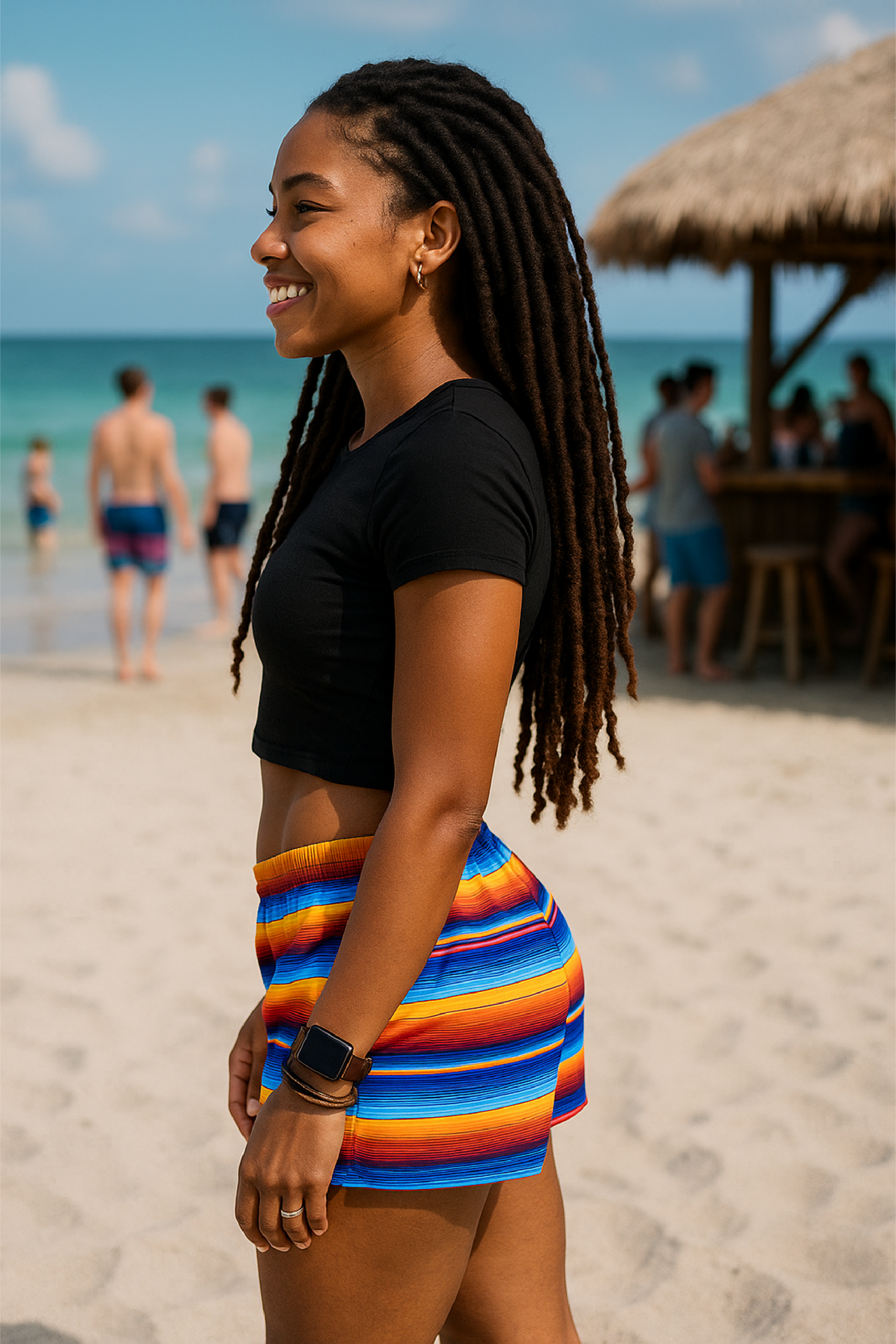Woman in a colorful skirt and black top on a beach with people in the background