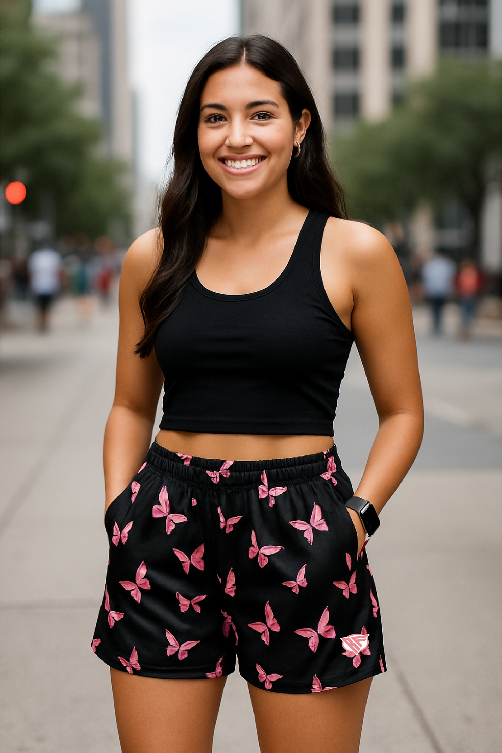 Woman wearing a black crop top and black shorts with pink butterfly pattern on a city street.