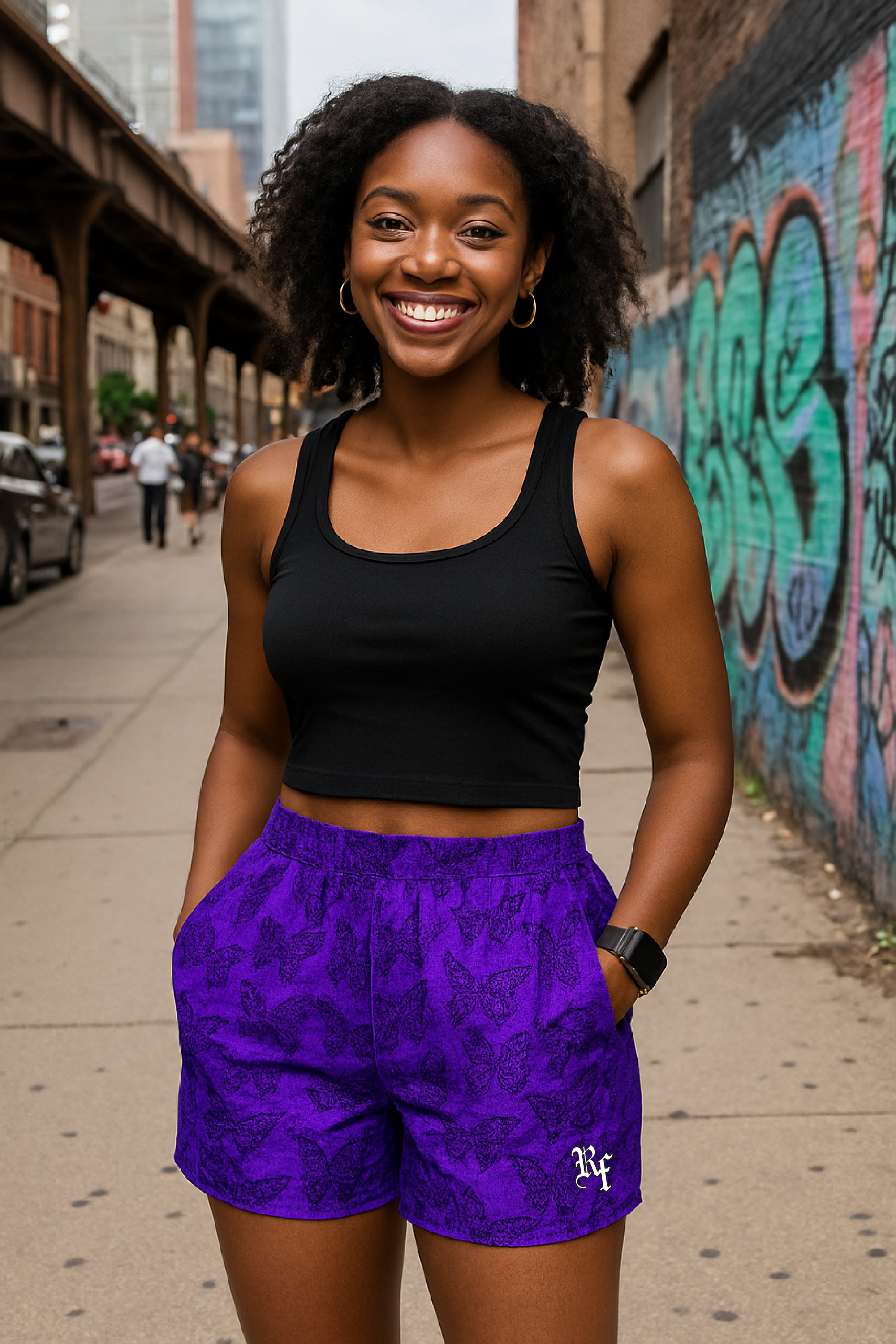 Woman wearing a black tank top and purple shorts/black butterflies with a city street and graffiti in the background