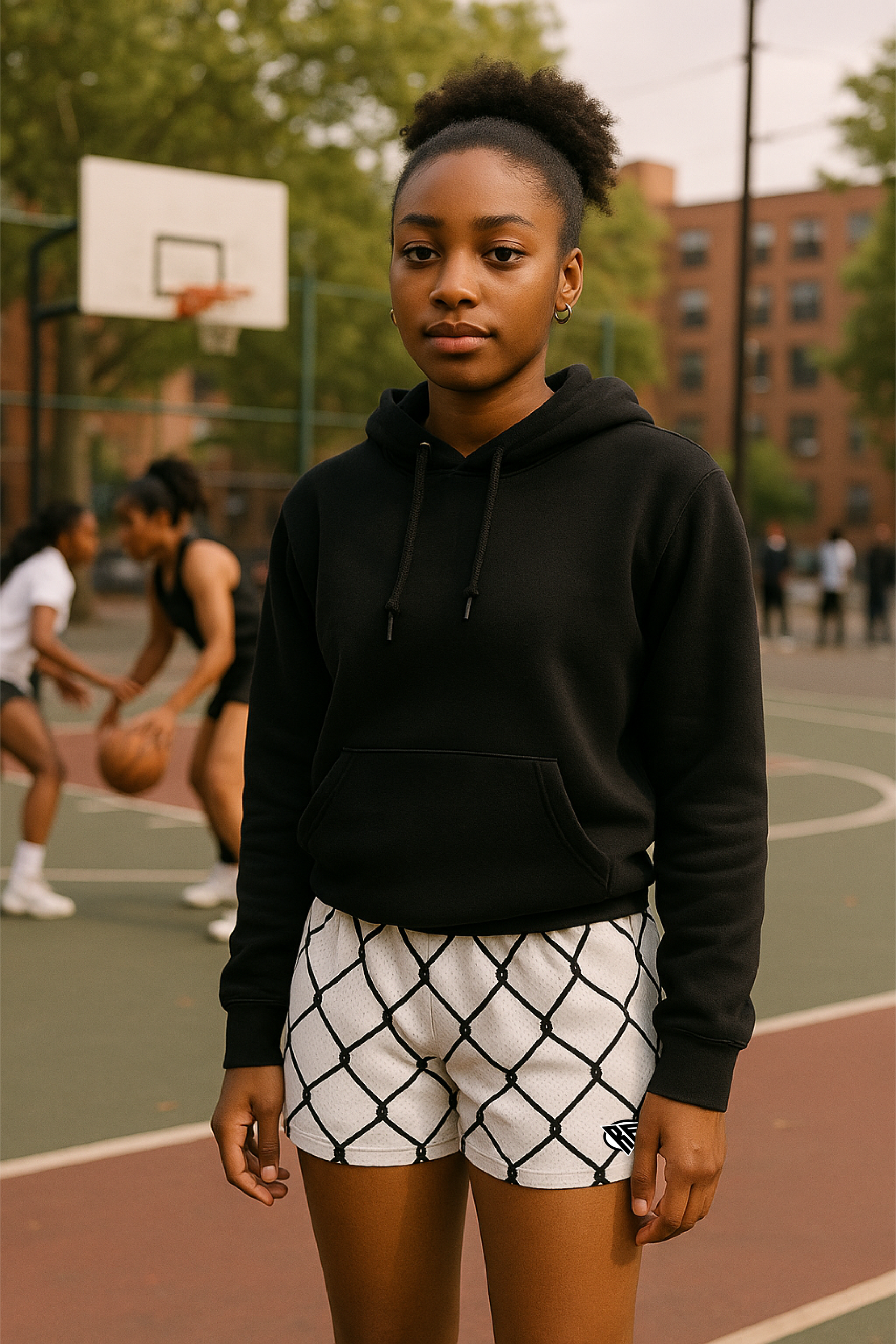 Person wearing a black hoodie and white shorts with black chain link pattern on a basketball court.