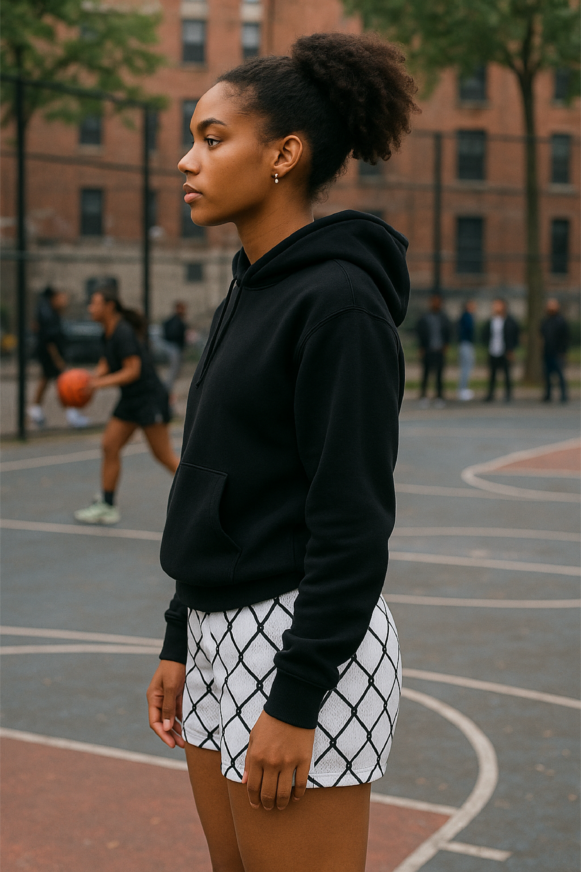 Person wearing a black hoodie and white shorts with black chain link pattern on a basketball court.