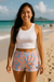 Woman wearing a white tank top and colorful shorts on a beach
