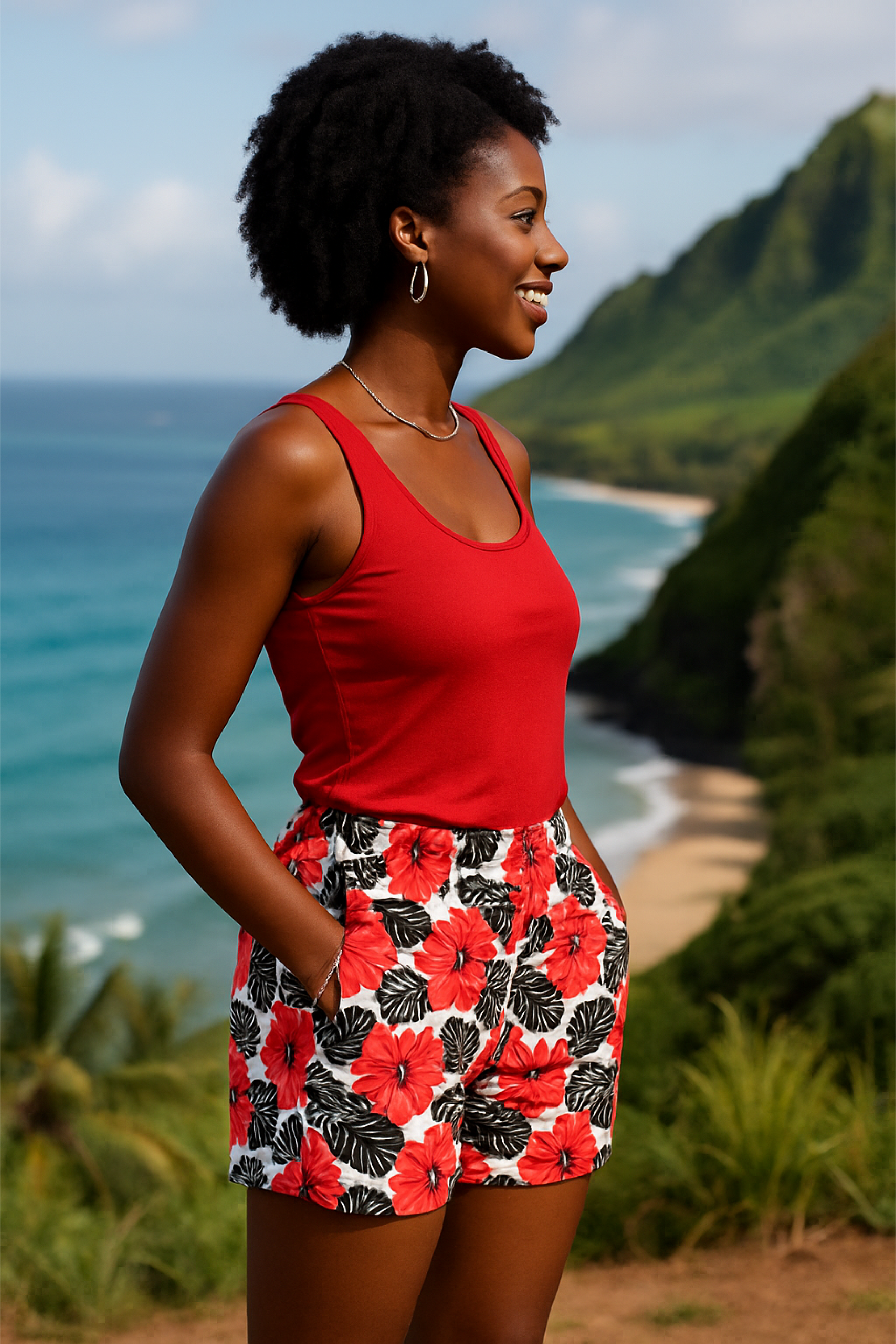 Woman in a red top and floral shorts standing in a scenic location with ocean and mountains.