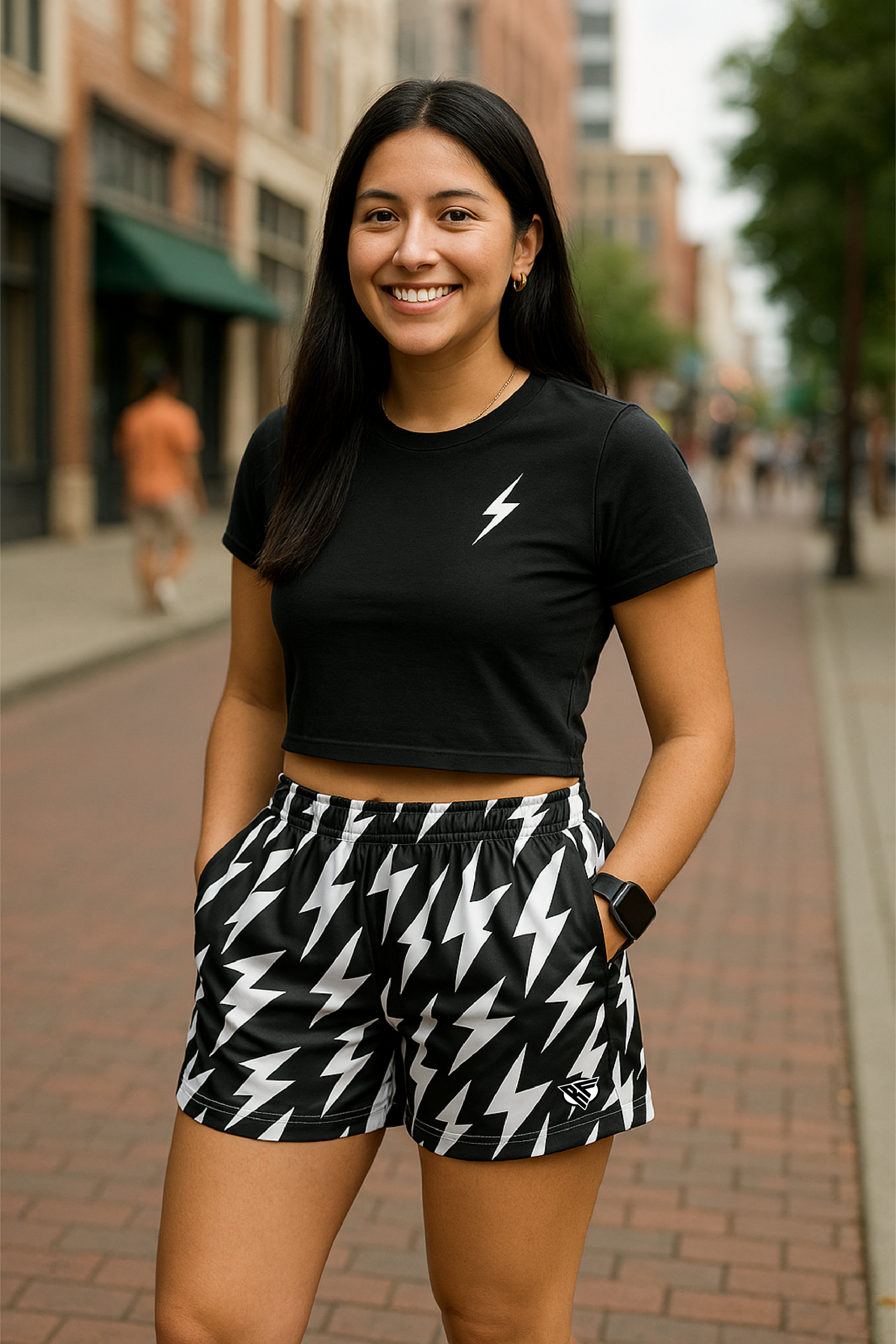 Woman wearing a black crop top and black and white lightning bolt patterned shorts on a city street.